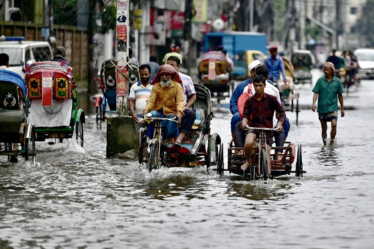 Commuters wade through a flooded street in Sylhet on June 20, 2024. Torrential rains in Bangladesh have triggered landslides burying alive at least nine people and forcing thousands to flee to higher ground, police and government officials in the low-lying nation said on June 19. In Sylhet, lashing rain and rivers swollen by flooding upstream in India also swamped heavily populated areas. (Photo by Mamun Hossain / AFP) (Photo by MAMUN HOSSAIN/AFP via Getty Images)